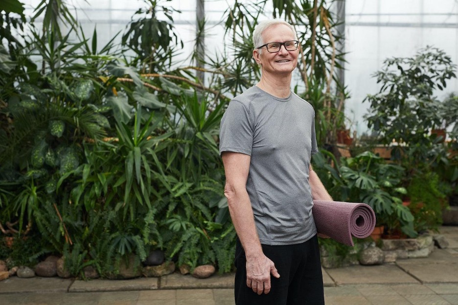 middle aged man smiling with a yoga mat