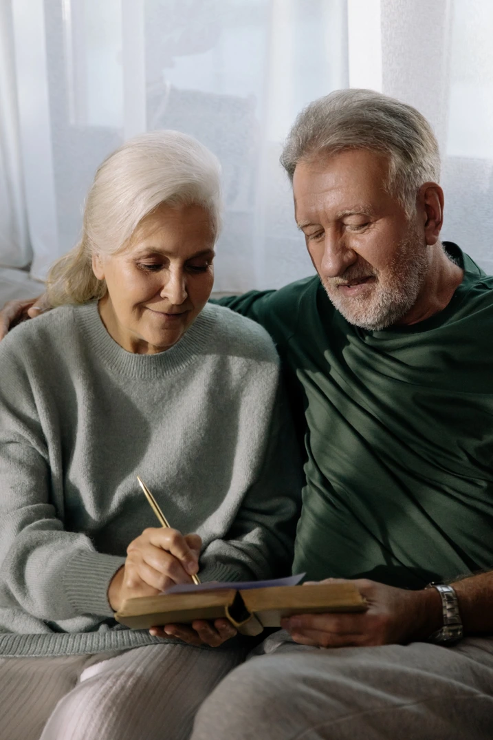 An older couple smiling while writing something down
